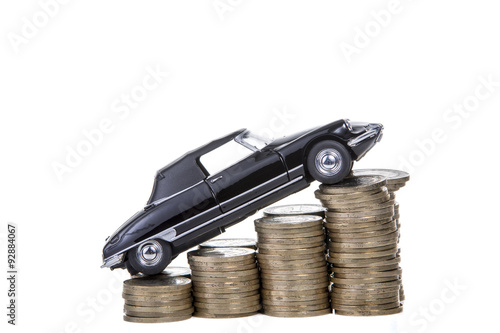 Price increase of car. / Black car over a lot of stacked coins.
