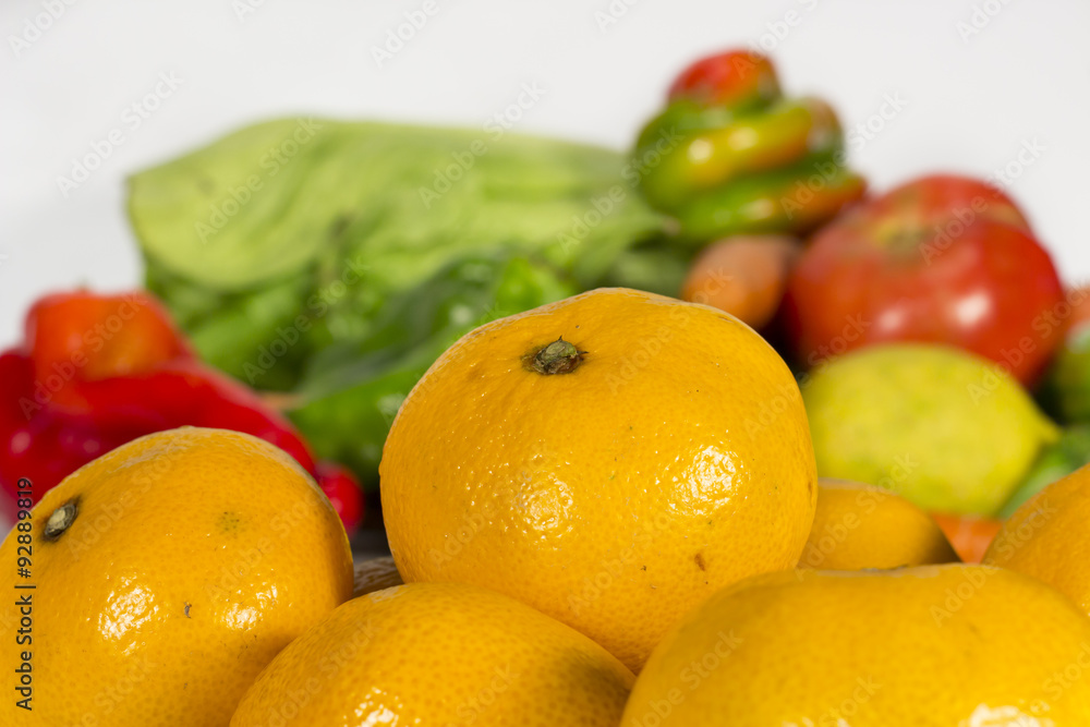 Orange tangerines in front of several fruits and vegetables Orange tangerines in front of several fruits and vegetables