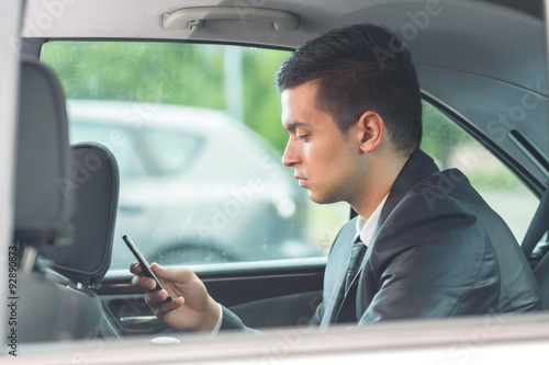 Young businessman using mobile phone while sitting on the back seat of the car © bokan