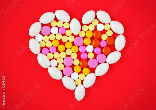 Colorful tablets arranged in a heart shape on red background.