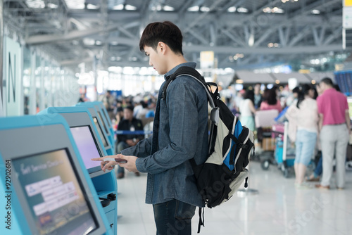 Young asian man using self check-in kiosks in airport