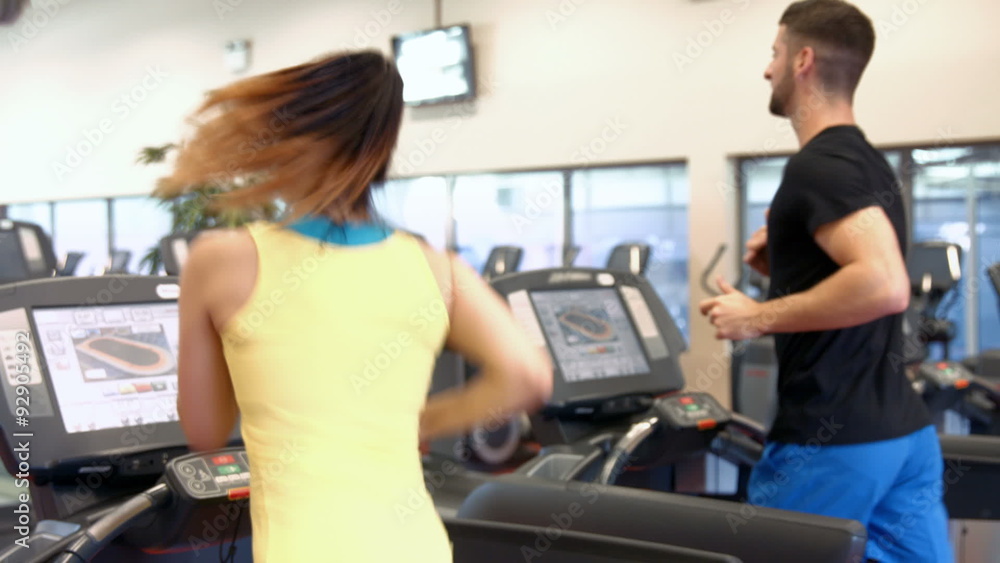 Couple using the treadmills in gym Couple using the treadmills in gym