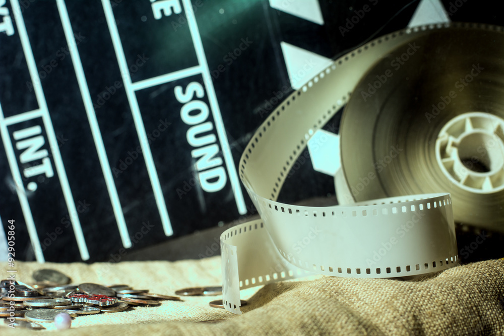 Fototapeta premium Cinema clapper and video film negative movie on a rough cloth.