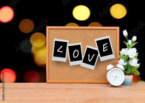 blur cork board with white clock and flower vase with bokeh ligh