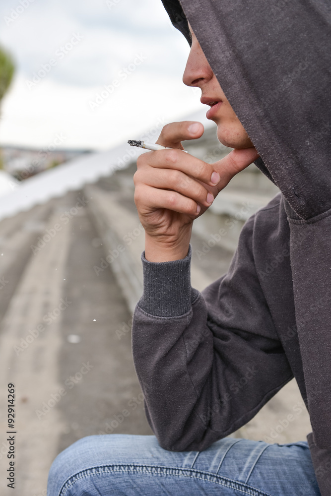 Young man in depression smoking a cigarette on a stadion. Concep Stock-foto  | Adobe Stock