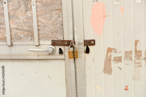 close up of a rusty steel door securely locked with a golden pad