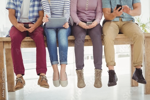 Low section of business people sitting on desk 