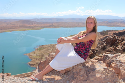 A young woman sit on the rock and look at the camera.
 photo