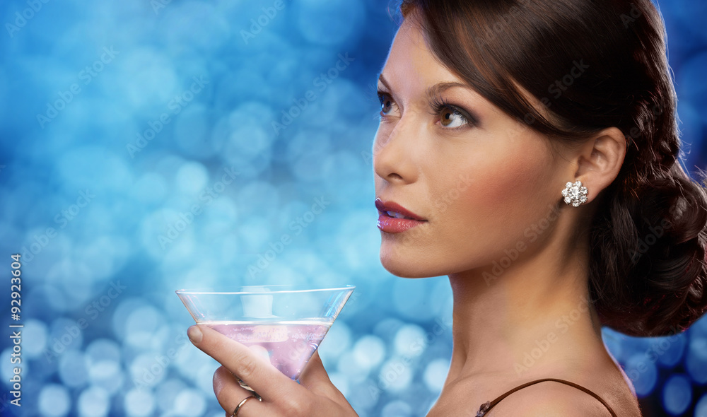 smiling woman holding cocktail over blue lights smiling woman holding cocktail over blue lights
