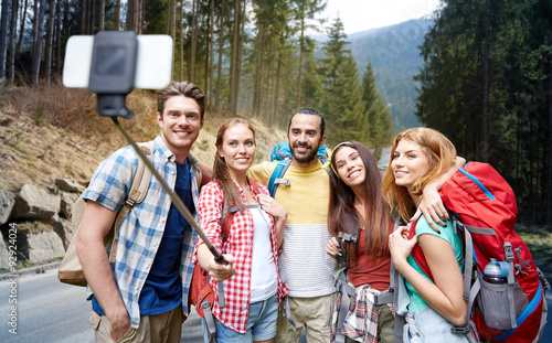friends with backpack taking selfie by smartphone