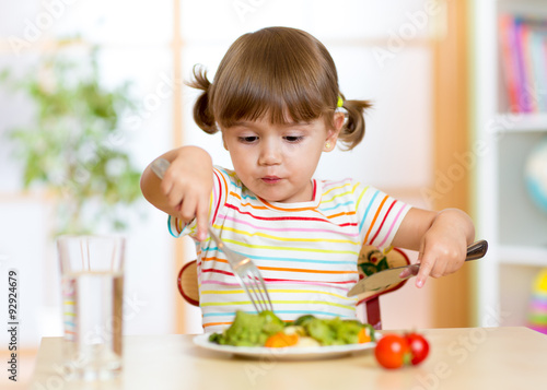 Obraz na plátně kid eating healthy food at home or kindergarten
