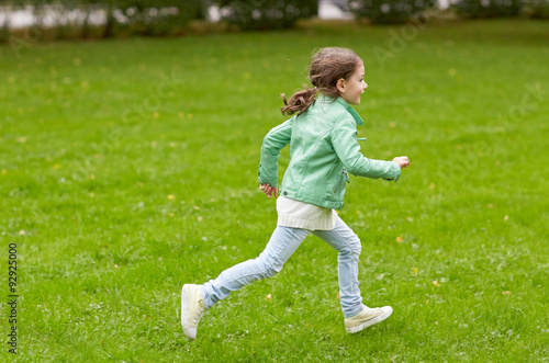 happy little girl running on green summer field