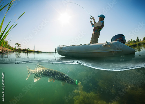Fotografia, Obraz Fisherman with rod in the boat and underwater view