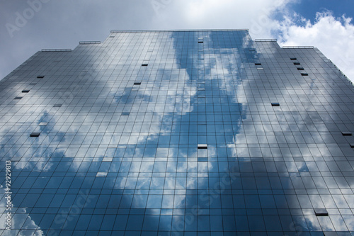 Abstract glass building reflecting clouds and blue sky