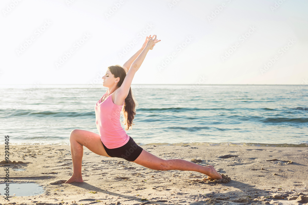 young caucasian female doing exercises on the seaside during the