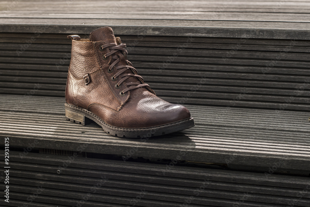 Mens leather boot on wooden stairs
