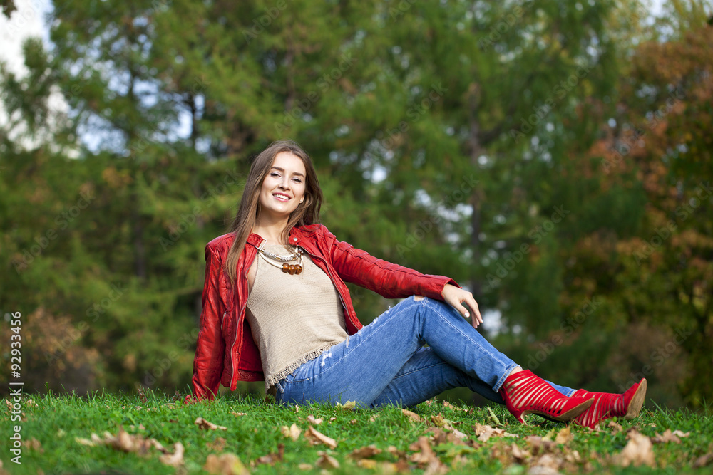Hppy beautiful woman in red leather jacket and blue jeans sittin Hppy beautiful woman in red leather jacket and blue jeans sittin