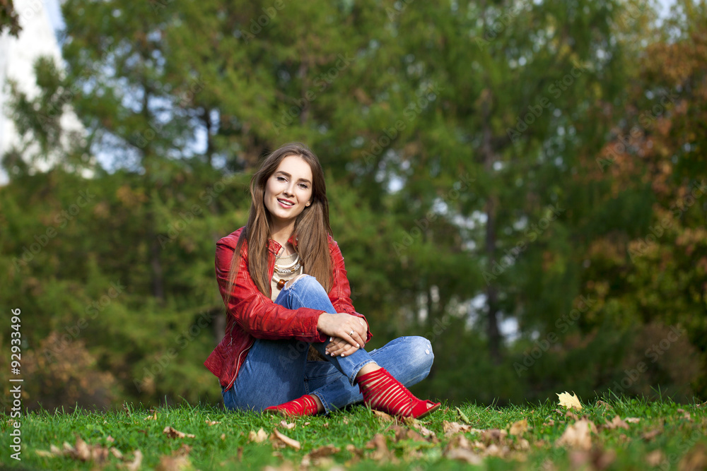 Hppy beautiful woman in red leather jacket and blue jeans sittin Hppy beautiful woman in red leather jacket and blue jeans sittin