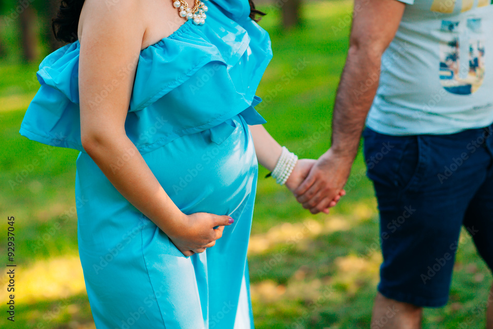 Beautiful pregnant couple relaxing outside in the park.