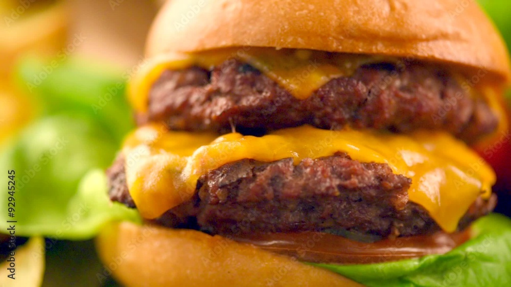 Cheeseburger on fresh buns with succulent beef patties and salad ingredients Cheeseburger on fresh buns with succulent beef patties and salad ingredients