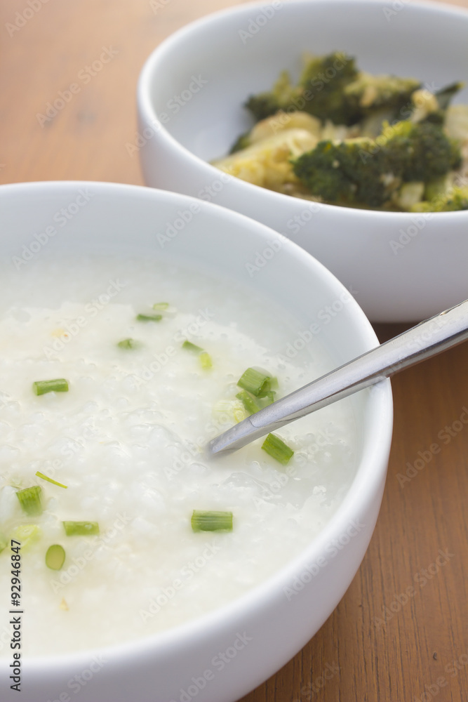 porridge and stir fried vegetable in white bowl on wooden table porridge and stir fried vegetable in white bowl on wooden table