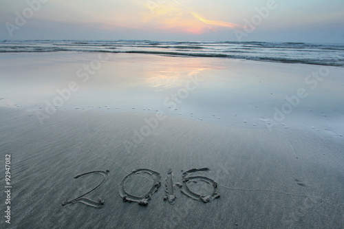Sandy beach with 2016 written on sand during dawn hours 