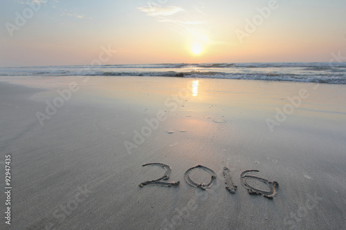 Sandy beach with 2016 written on sand with sunrise in background