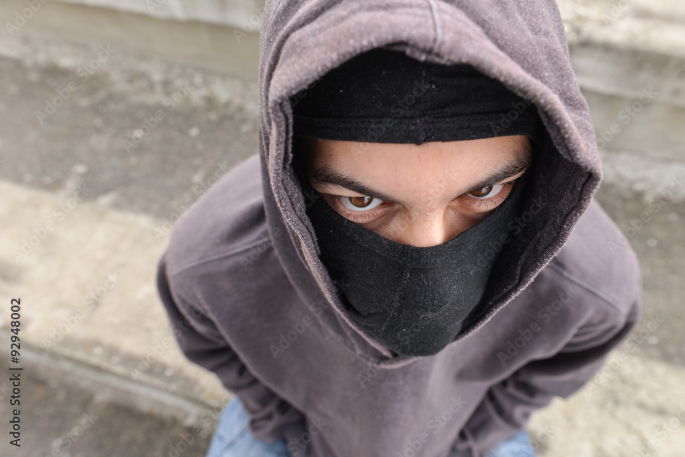 unrecognizable young man wearing black balaclava sitting on old