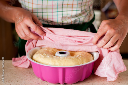 A Woman Taking the Towel off the Raised Yeast Dough Roulade