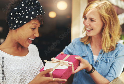Foto Young woman giving a friend a surprise gift