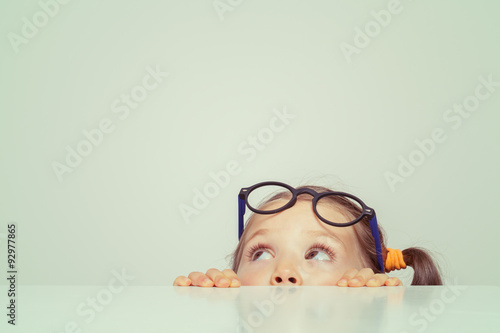 cute little girl hiding behind the table