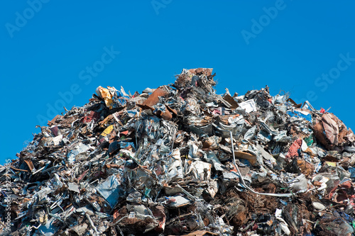 Pile of scrap metal over blue sky.
