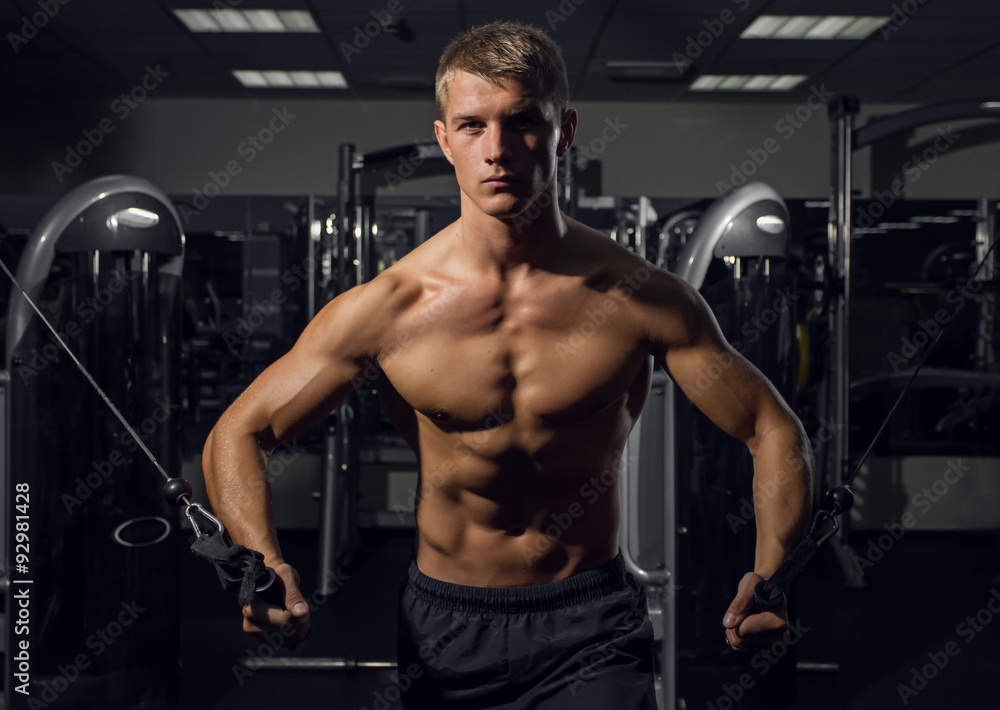 Young athletic man pumping up muscles on crossover Young athletic man pumping up muscles on crossover