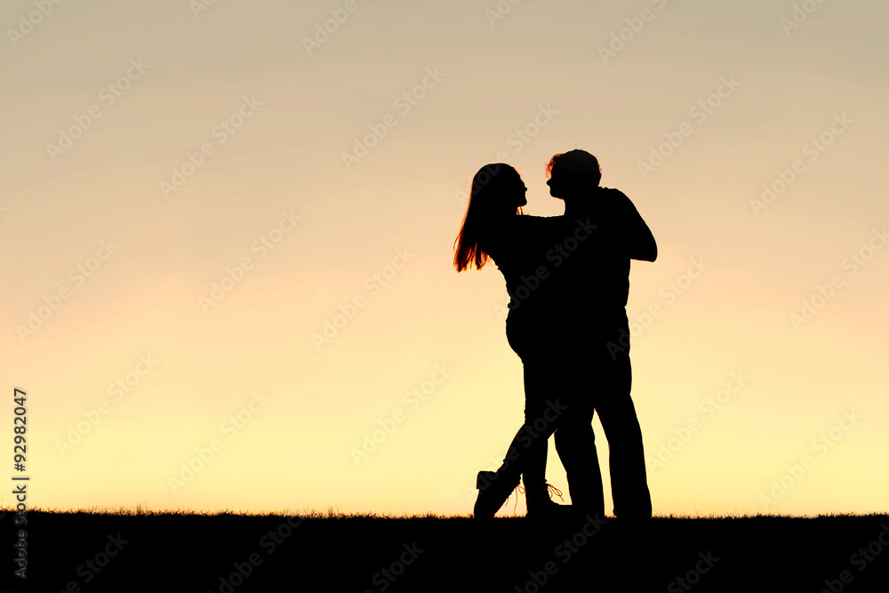 Silhouette of Happy Young Couple Dancing at Sunset