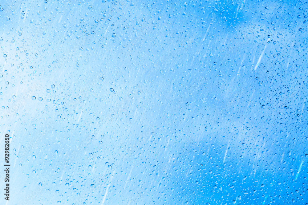Drops of rain on blue glass background. The sky with clouds on background.