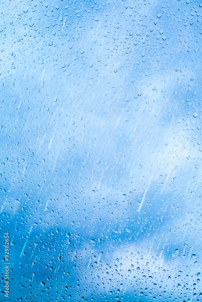 Drops of rain on blue glass background. The sky with clouds on background.