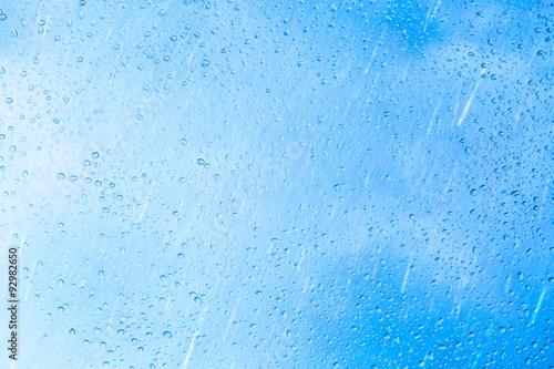 Obraz na płótnie Drops of rain on blue glass background. The sky with clouds on background. w salonie