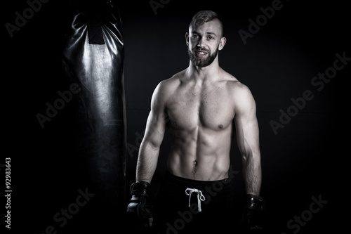 Male Athlete boxer punching a punching bag with dramatic edgy li