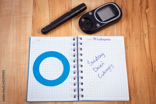 Polish inscription world diabetes day in notebook, blue circle and glucometer, symbol of diabetic