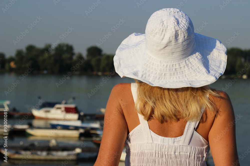  A woman with a hat relaxes by the river 