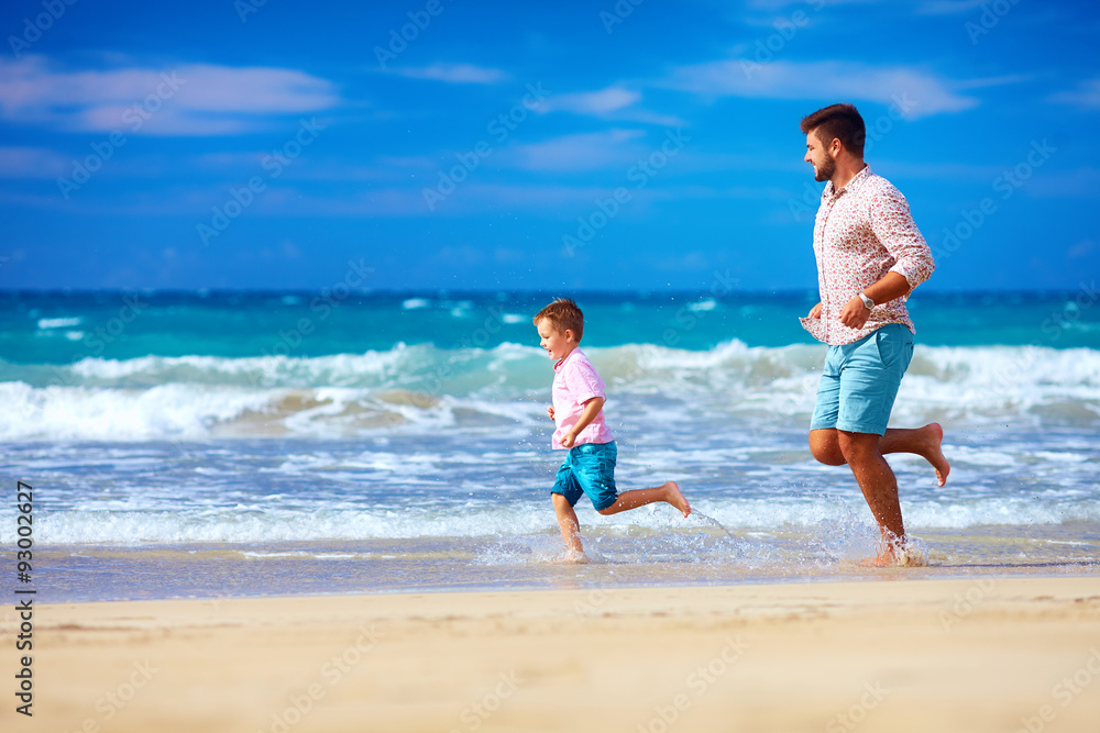 happy excited father and son running on summer beach, enjoy life