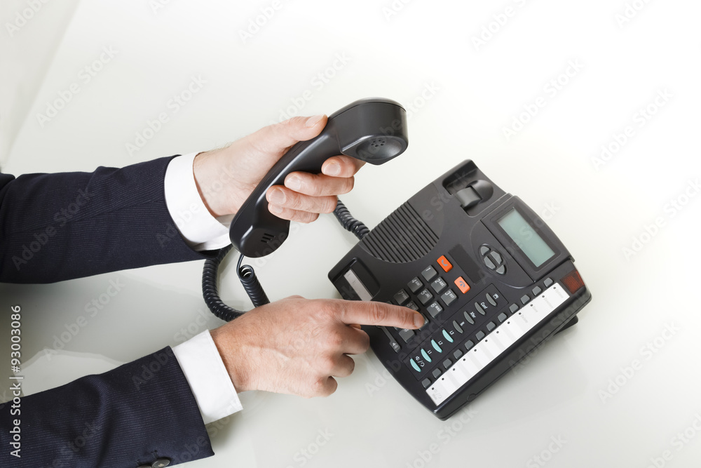 Top view of businessman hands dialing out on a black deskphone Top view of businessman hands dialing out on a black deskphone