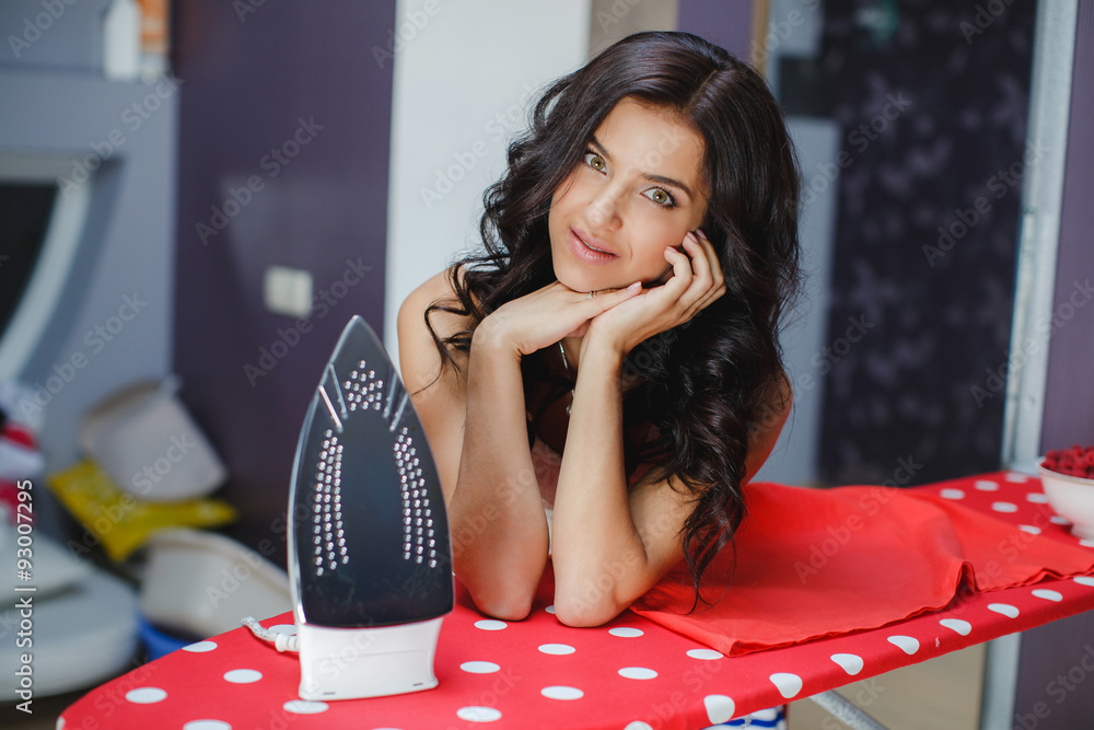 Fototapeta premium Happy young beautiful woman ironing clothes.