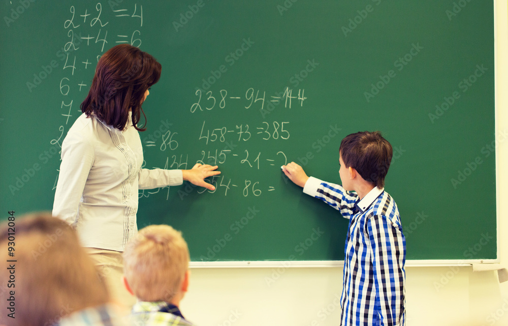 schoolboy with math teacher writing on chalk board schoolboy with math teacher writing on chalk board