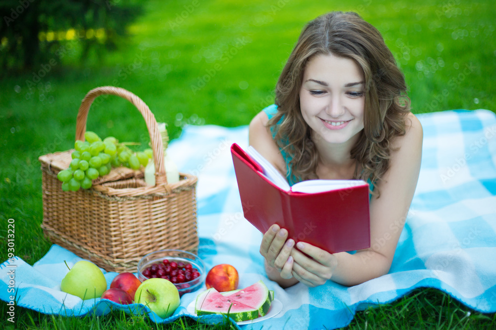 young beautiful woman with picnic basket and fruits reading book young beautiful woman with picnic basket and fruits reading book