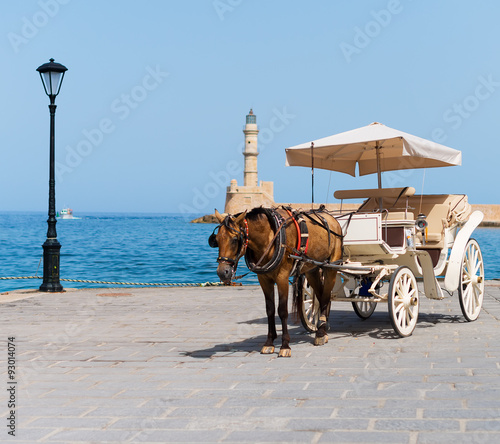 Horse and vintage carriage on the pier near the sea.