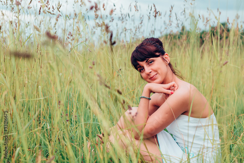 Quadro su tela beautiful Russian girl sits in a meadow