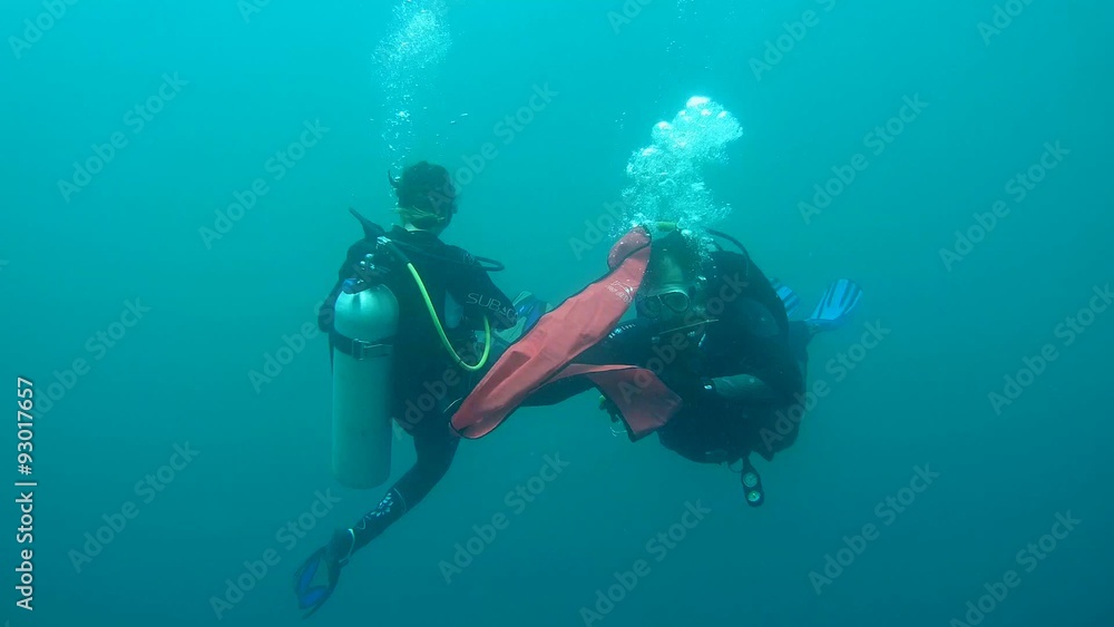 Divers man and a woman floating in the water and start a signal buoy
Divers man and a woman floating in the water and start a signal buoy