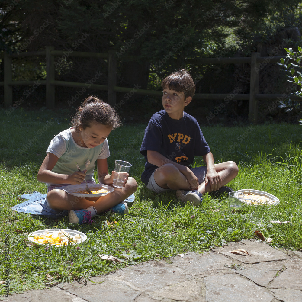 Niños comiendo en el campo con platos y vasos de plástico