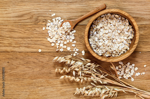 Rolled oats and oat ears of grain on a wooden table photo